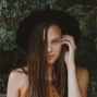 a brown haired woman wearing a black round hat