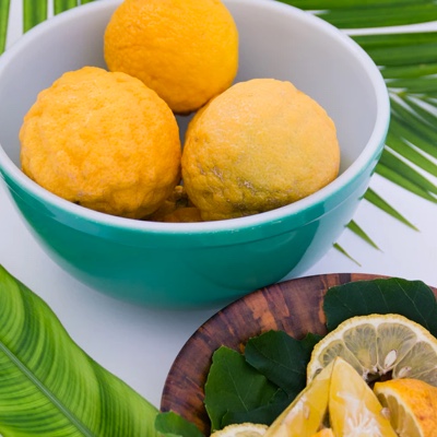 a bowl with some whole lemons with a plate of cut up lemons on the side
